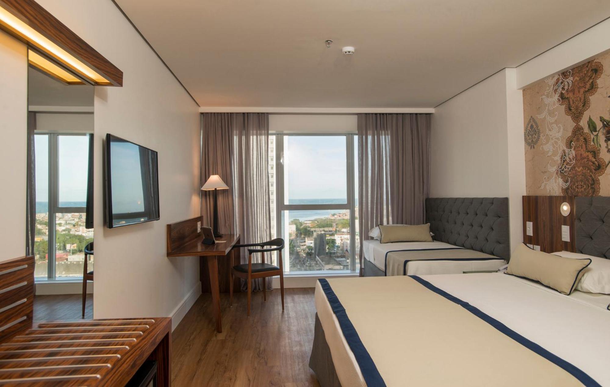 Hotel Luzeiros Recife Dış mekan fotoğraf The photo shows a hotel room that features a modern and comfortable design. There are two beds: one larger bed and a smaller twin bed. The room has large windows with curtains that allow natural light to enter, offering a view of the outside, possibl